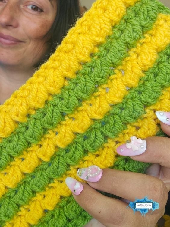 Close-up of yellow and green striped crochet fabric with a textured stitch pattern