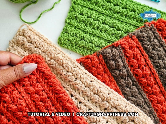Several textured crochet swatches in green, beige, orange, and brown show raised rows of the Braided Leaves Stitch, with one orange swatch held in a hand. The Braided Leaves Stitch was created by Ariana Wimsett, a known crocheter and author, and the crochet work shown here was also made by her.