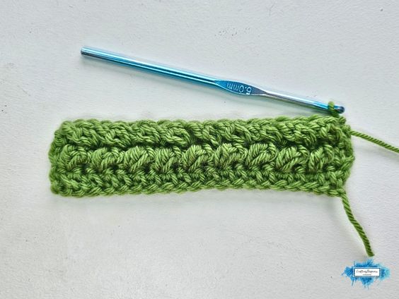 A green crochet swatch shows another view of Row 3 of the Braided Leaves Stitch, with raised leaf-like sections beginning to form across the row. The Braided Leaves Stitch was created by Ariana Wimsett, a known crocheter and author, and the crochet work shown here was also made by her.